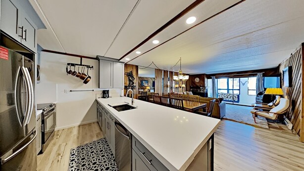 Una cocina moderna con una isla grande, electrodomésticos de acero inoxidable y una zona de comedor con una mesa y sillas de madera.