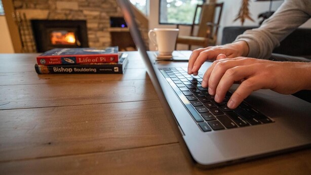 A laptop on a wooden table with books and a cup. - Large Upgraded 4 Bedroom Condo in Mammoth! Easy access To Hot Tubs, Pool, Sauna by RedAwning (Mammoth Lakes)