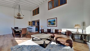 A spacious living area with a leather sofa, a dining table, and a kitchen in the background. - Large Upgraded 4 Bedroom Condo in Mammoth! Easy access To Hot Tubs, Pool, Sauna by RedAwning (Mammoth Lakes)