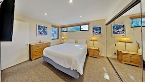 Une chambre à coucher avec un grand lit, deux tables de chevet avec des lampes, une commode et un grand miroir.