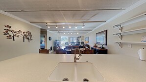 Una cocina con una isla central, un comedor con sillas, una estufa y un ventanal grande.