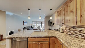 A kitchen with granite countertops, wooden cabinets, and pendant lighting. - Stay mountainside! One Bedroom Condo Just Steps to the Mountain and 1 Mile to the Village at Mammoth by RedAwning (Mammoth Lakes)