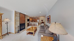 A modern living room with a fireplace, a dining area, and a kitchen in the background. - Stay mountainside! One Bedroom Condo Just Steps to the Mountain and 1 Mile to the Village at Mammoth by RedAwning (Mammoth Lakes)