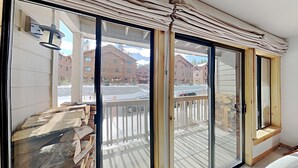 A room with a sliding glass door leading to a balcony with a view of buildings and a snowy landscape. - Stay mountainside! One Bedroom Condo Just Steps to the Mountain and 1 Mile to the Village at Mammoth by RedAwning (Mammoth Lakes)