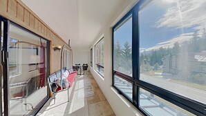 A corridor with large windows, a seating area with chairs, and a view of a road and trees.
