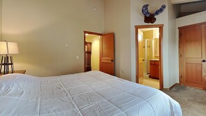A hotel room with a large bed, a wooden door, and a bathroom visible through an open door. - Beautiful Mountainside 4 BR Plus Loft/4 Bath Home in Mammoth! by RedAwning (Mammoth Lakes)
