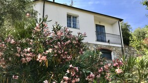 Ein zweistöckiges Gebäude mit Steinsockel und weißen Wänden, mit einem Balkon und Metallgeländern.