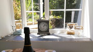A room with a window sill featuring a vintage clock, a bottle, and decorative jars. - 1 Bed Cottage-sleeps 3-pool-pets-near St Ives (Camborne)