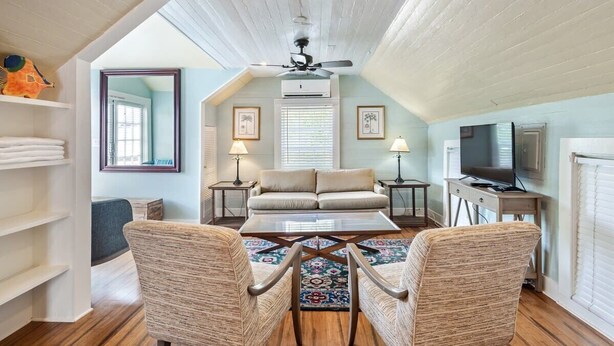 A cozy living room with a sofa, two armchairs, a coffee table, and a TV. - Sky Loft - Steps from Duval Street & Shared Pool (Key West)