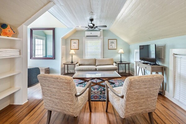 A cozy living room with a sofa, two armchairs, a coffee table, and a TV. - Sky Loft - Steps from Duval Street & Shared Pool (Key West)