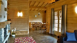 Ein Holzinnenraum mit Kamin, Essbereich und einer Sitzecke mit Sofa und Sesseln.