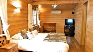 Ein Zimmer in einer Holzhütte mit einem Bett, einem Fernseher und einem Schminktisch.