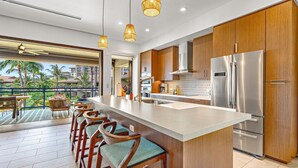 A modern kitchen with a large island, stainless steel appliances, and wooden cabinets.