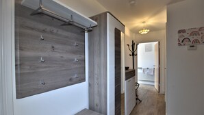 Ein moderner Flur mit einer Holzvertäfelung, einem Kleiderständer und einer Treppe zu einem anderen Raum.