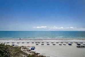 A beach with rows of blue boats, a sandy shore, and a clear blue sky.