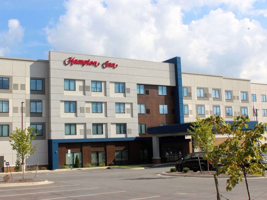 Ein Hampton Inn Hotel mit moderner Fassade, zahlreichen Fenstern und einem Parkplatz.