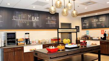 A breakfast buffet area with a variety of food items, a coffee station, and a chalkboard with kitchen-related drawings.