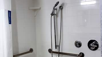 A bathroom with a bathtub, a shower with a handheld showerhead, and grab bars.
