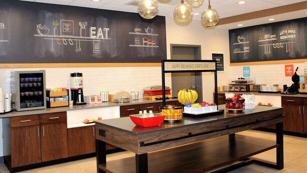 A breakfast bar with a chalkboard menu, a coffee machine, and various food items. - Hampton Inn Lexington, NC (Lexington)