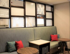 A seating area with a sofa, a small table, and a printer. - Hampton Inn Lexington, NC (Lexington)