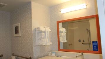 Un baño con lavamanos, espejo, toallero y retrete.