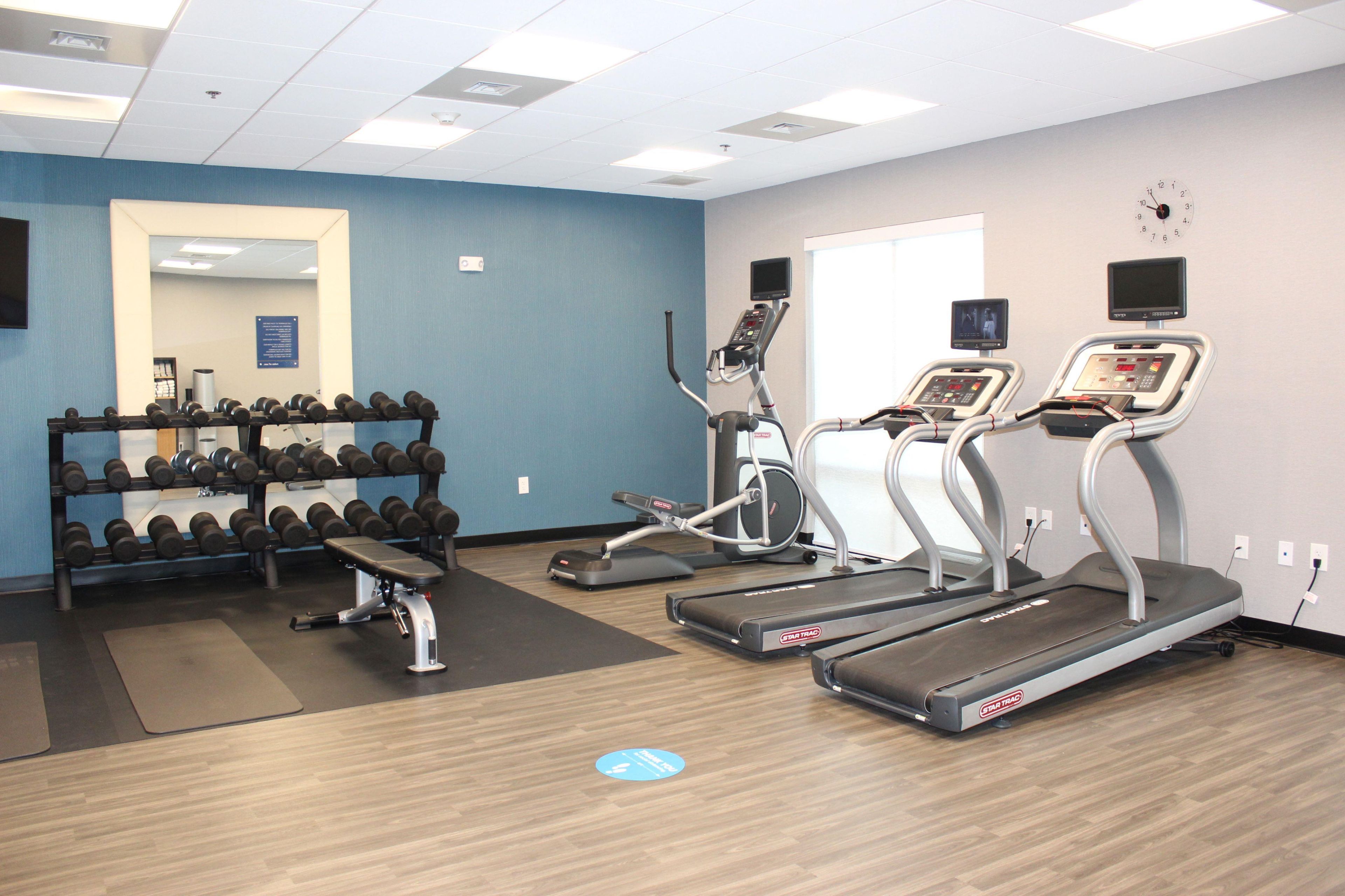 A gym with treadmills, a bench press, and a rack of dumbbells.
