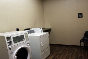 A laundry room with a front desk sign, a washing machine, and a dryer. - Hampton Inn Lexington, NC (Lexington)