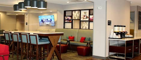 A hotel lobby with a conference table, seating area, and a coffee station.