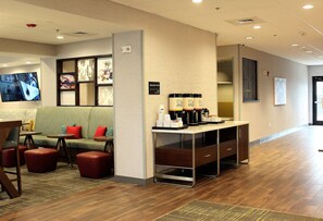 A hotel lobby with a seating area, a coffee station, and a television screen. - Hampton Inn Lexington, NC (Lexington)
