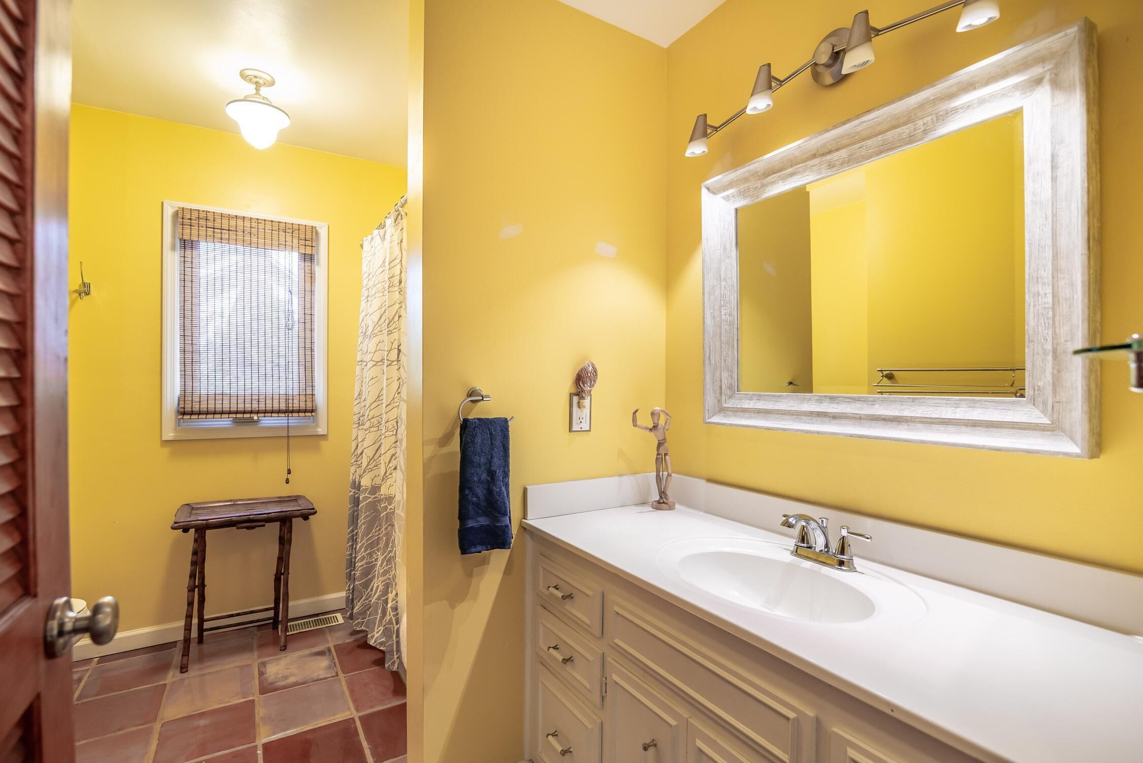 A bathroom with yellow walls, a white sink, and a large mirror.