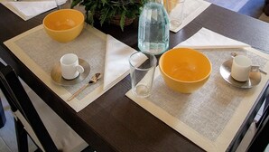 Ein Esstisch, gedeckt mit gelben Schüsseln, weißen Tassen und einer dekorativen Mitte.
