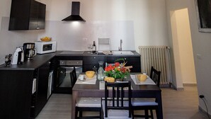 Eine moderne Küche mit Essbereich, ausgestattet mit einer zentralen Kochinsel, dunklen Schränken und einer dekorativen Decke.