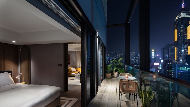 A modern hotel room with a balcony, a bed, a seating area, and a city view. - The Hari Hong Kong (Hong Kong)