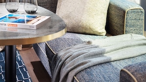 A modern hotel room with a city view, a round table with two glasses and a book, and a cozy seating area with a blanket. - The Hari Hong Kong (Hong Kong)