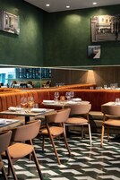 Un restaurante con cabinas y mesas, piso estampado y obras de arte en las paredes.