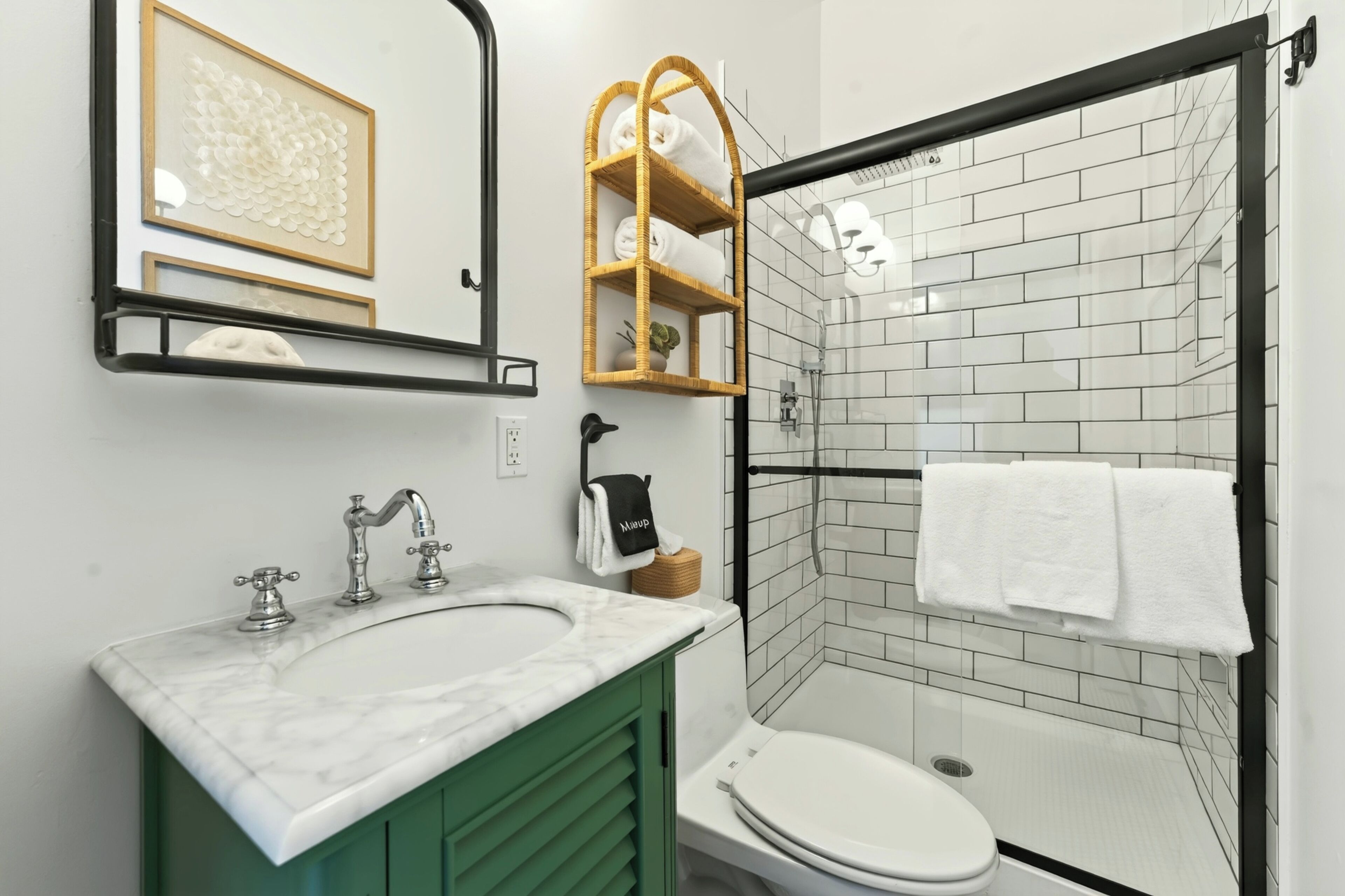 A modern bathroom with a glass shower enclosure, a marble sink, and a green vanity.