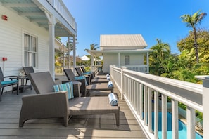 A covered outdoor area with wicker furniture and a pool.