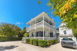 A two-story white house with a balcony, a driveway, and a parked car. - FLOR DE CANA ~ Adults Only, Queen Room w/Pool View at Azul Mansion! (Key West)