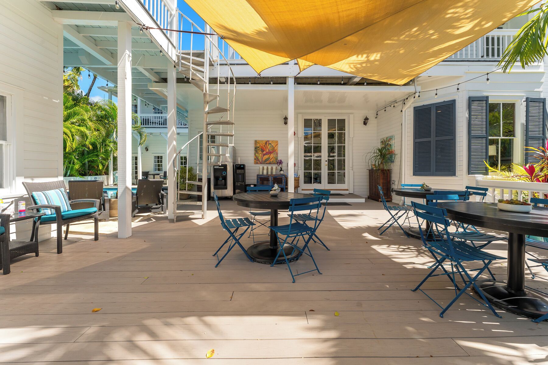 A covered outdoor patio with a pool, blue chairs, and a table.