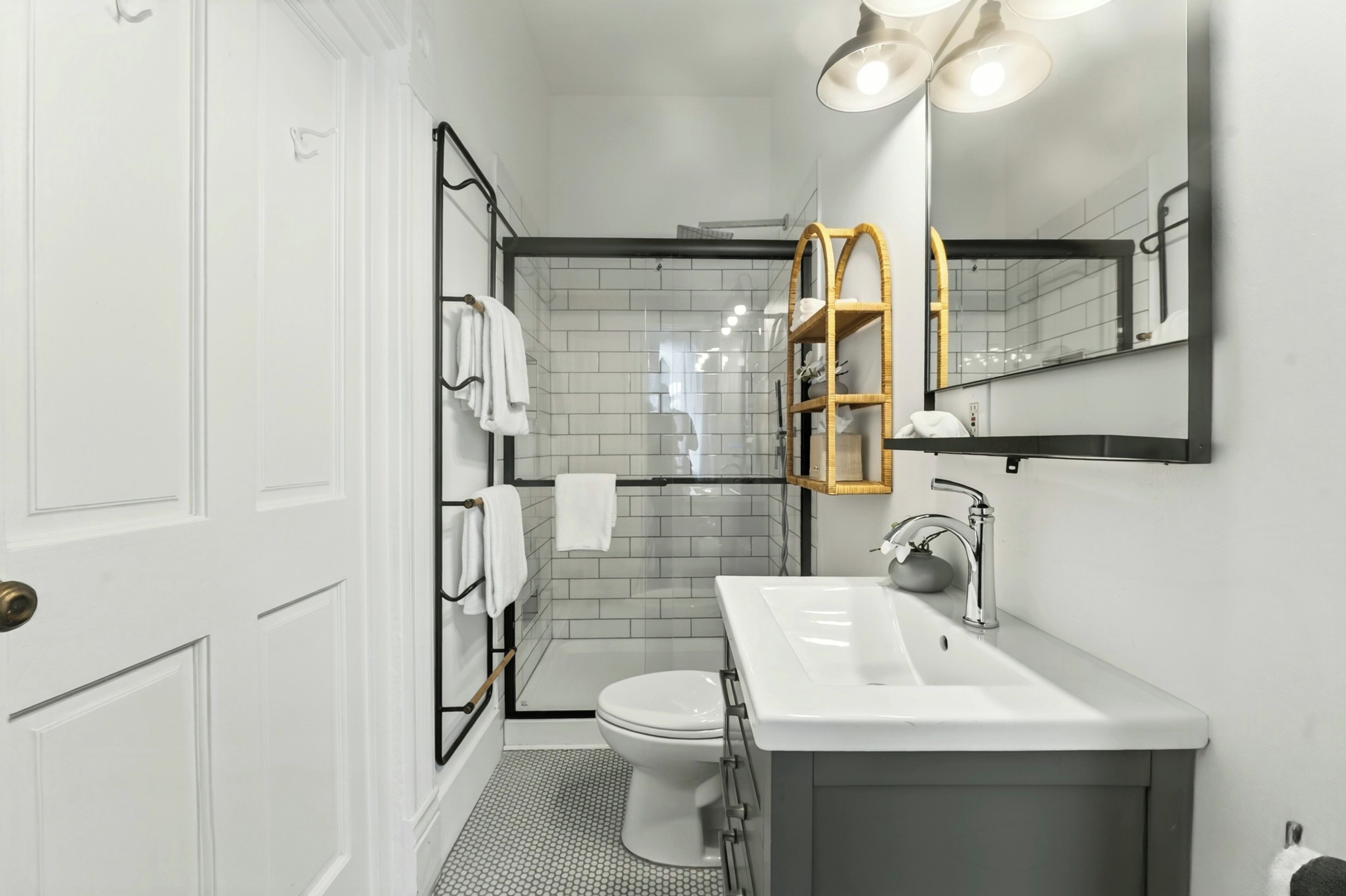 A modern bathroom with a white toilet, a white sink, and a glass shower enclosure.
