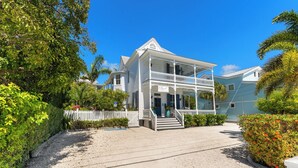 A two-story white building with a balcony, surrounded by greenery and a white picket fence. - CAPTIVA ~  Adults Only,  King Room with Community Pool at Azul Mansion! (Key West)