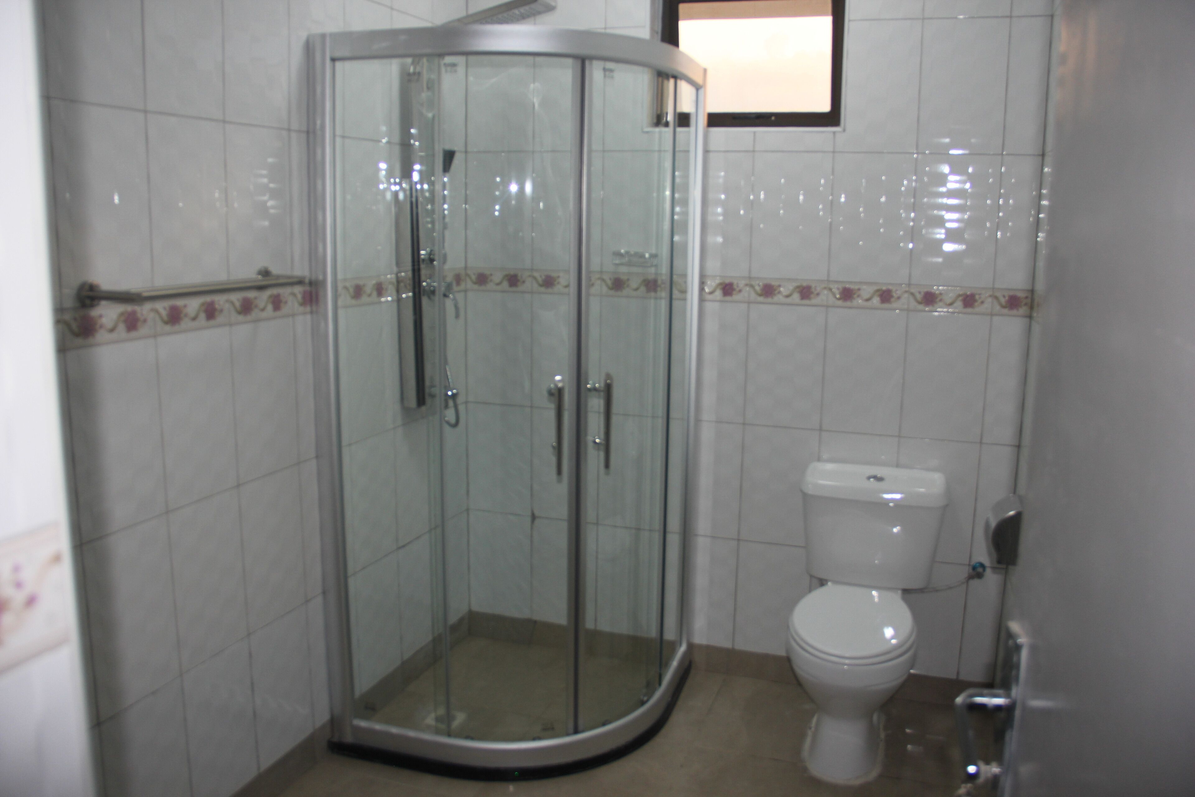 Un baño con ducha de vidrio, inodoro y paredes con azulejos.