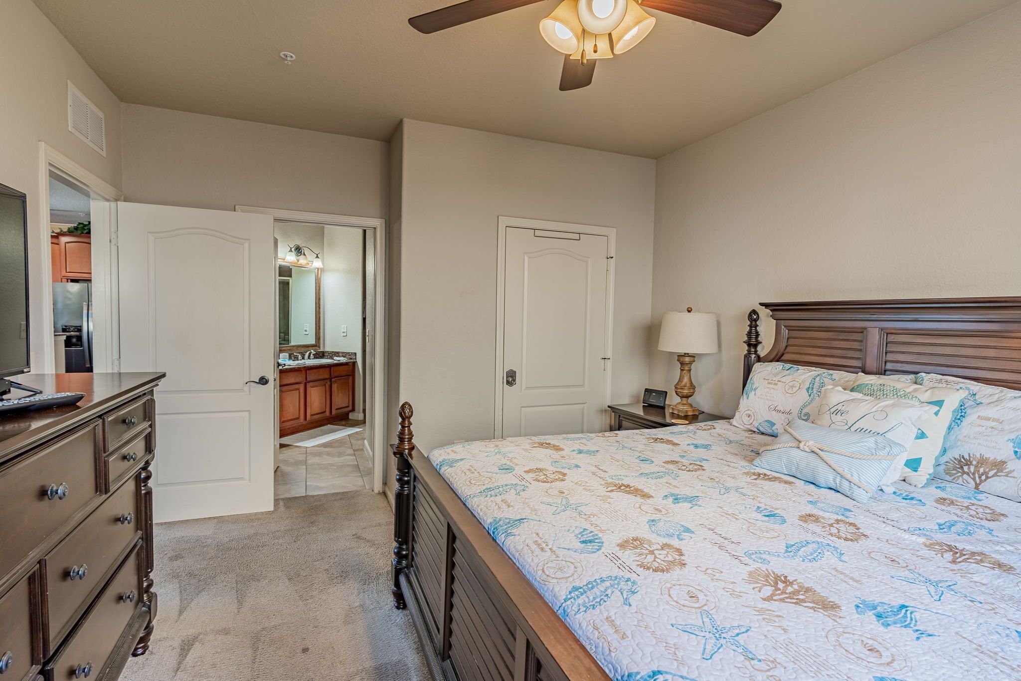 A bedroom with a bed, dresser, nightstand, and a ceiling fan.