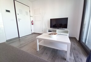 A modern room with a white TV stand, a white table, and a bowl of food.