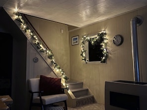 A staircase with a garland of lights, a clock, and a fireplace. - Creek Side Cottage with Lake Views, Lake Access, Dock and Secluded Yard (Jamestown)