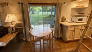 Een gezellige keuken met een eettafel, stoelen, een lamp, een magnetron en uitzicht op de omgeving.