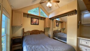 Een slaapkamer met een groot bed, houten hoofdbord, een plafondventilator en een raam dat natuurlijk licht binnenlaat.