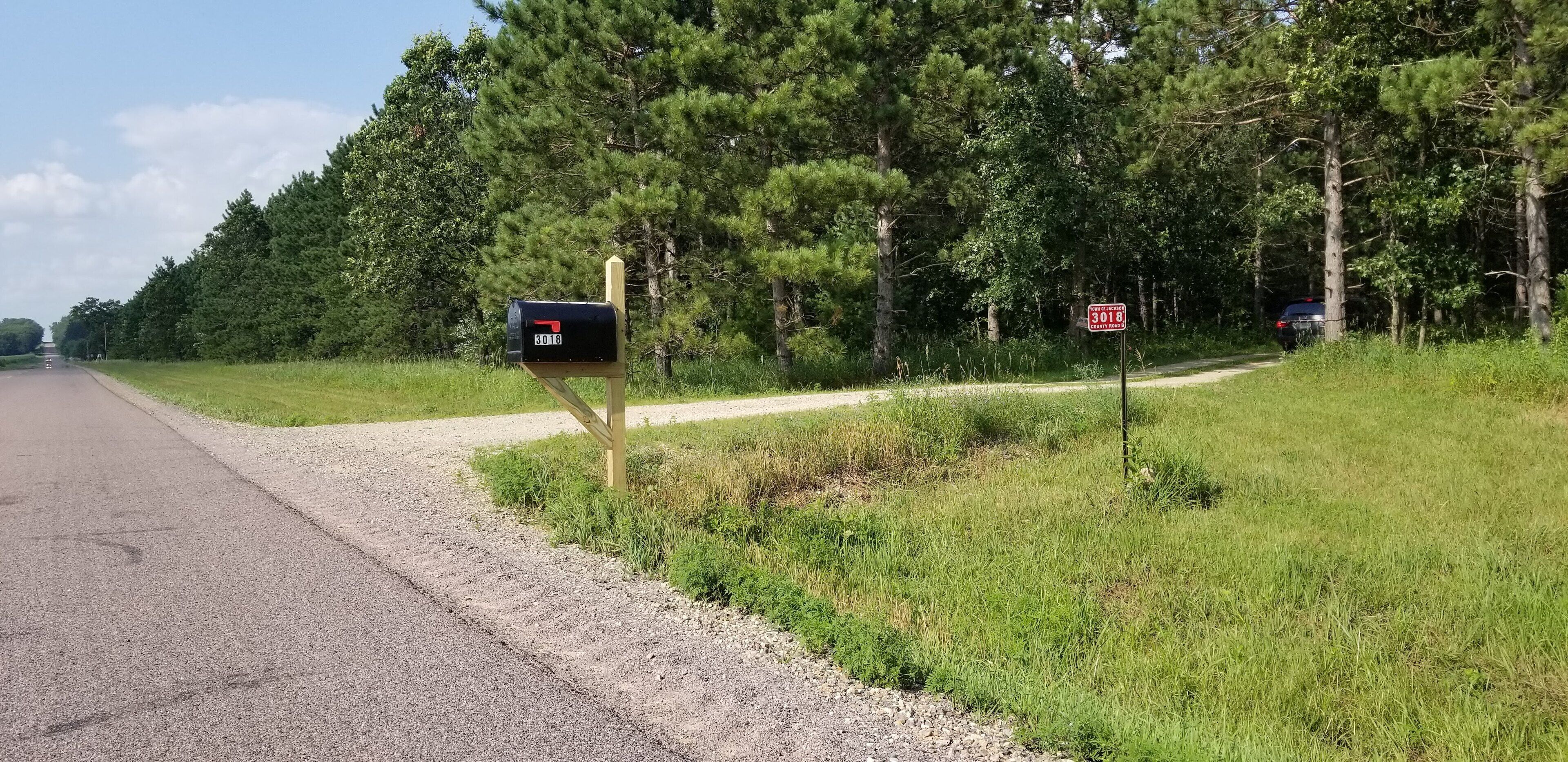 Eine Landstraße mit einem Briefkasten links und einem Stoppschild rechts.