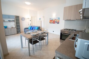 A modern kitchen with a dining area, featuring a stove, oven, and a dining table with chairs. - Central Suite Moniga (Moniga del Garda)