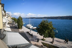 A waterfront promenade with boats docked, trees, and a clear blue sky. - Romantic Benaco Salò - App. 02 (Salò)